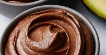 Creamy chocolate mousse topped with avocado and banana slices, a healthy dessert option.