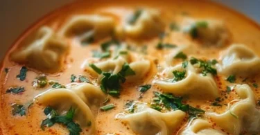 Bowl of creamy Thai Dumpling Soup garnished with fresh herbs and spices