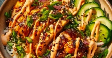 Crispy chicken with spicy sauce served over jasmine rice, a savory dish.