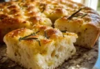Freshly baked homemade gluten-free focaccia bread topped with herbs and olive oil.