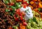 Colorful sweet potato taco bowl with toppings and ingredients.