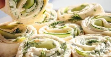 Plate of Cucumber Dill Pinwheels appetizer rolls with fresh ingredients.