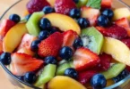 Colorful fruit salad drizzled with honey lime dressing, showcasing fresh fruits.