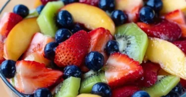 Colorful fruit salad drizzled with honey lime dressing, showcasing fresh fruits.