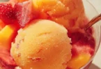 A bowl of vibrant mango strawberry sorbet served on a sunny day.