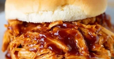 Crockpot BBQ chicken served with sides on a wooden table